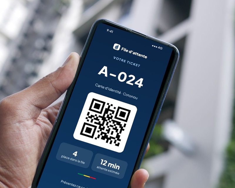 Un téléphone affiche un ticket avec son QR code, la place dans la file et l'attente estimée
